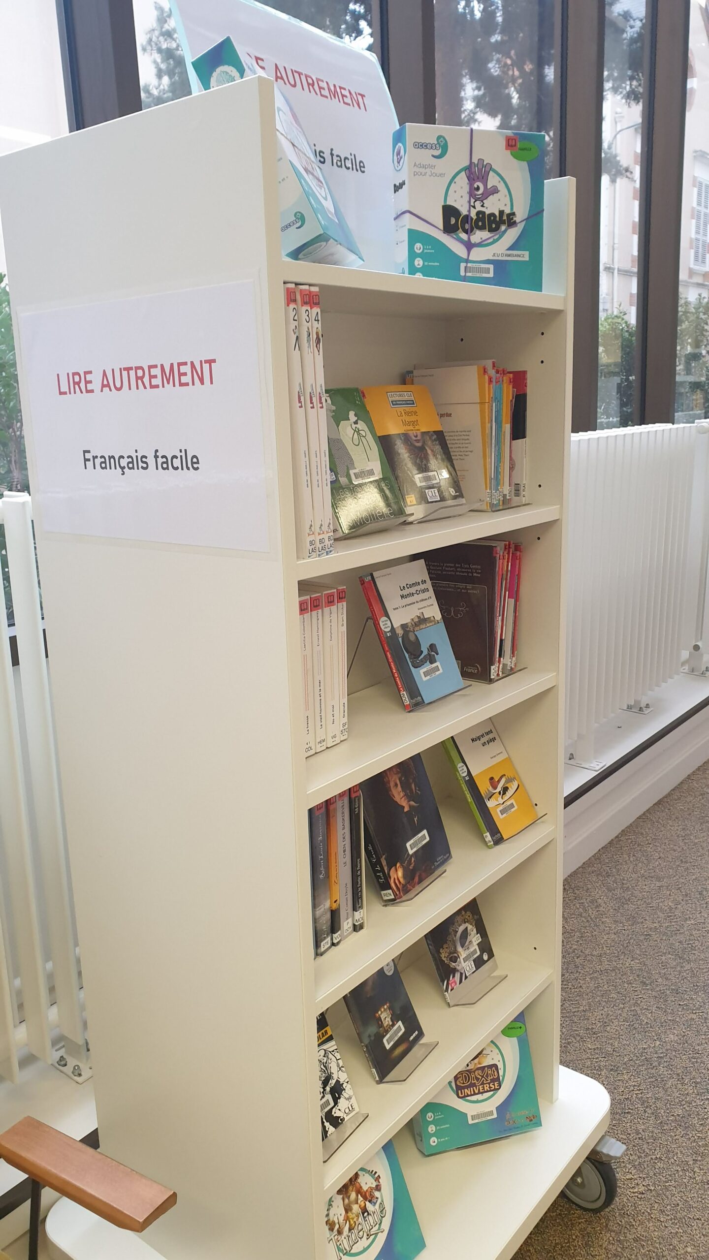 Un présentoir de bibliothèque affiche une sélection de livres « Lire autrement – Français facile », rangés sur plusieurs étagères et destinés à un public cherchant des lectures simplifiées.